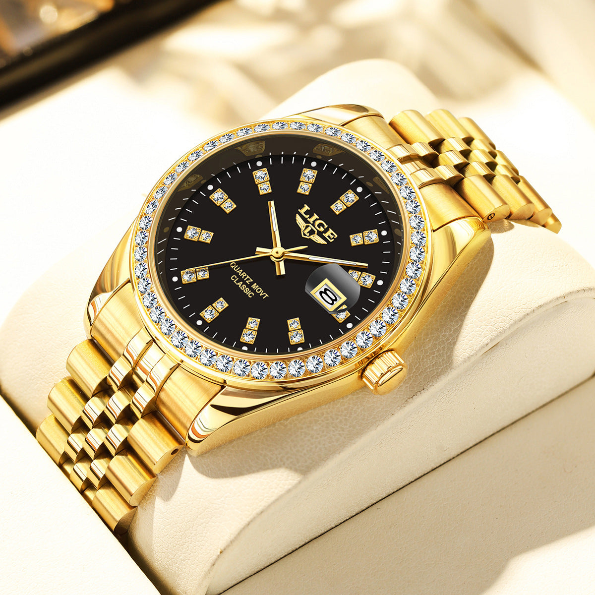 Gold wristwatch with black dial and diamond accents on a beige cushion