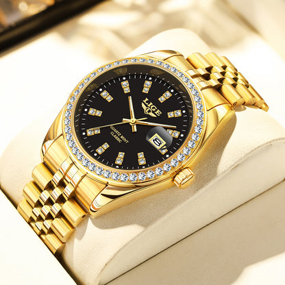 Gold wristwatch with black dial and diamond accents on a beige cushion